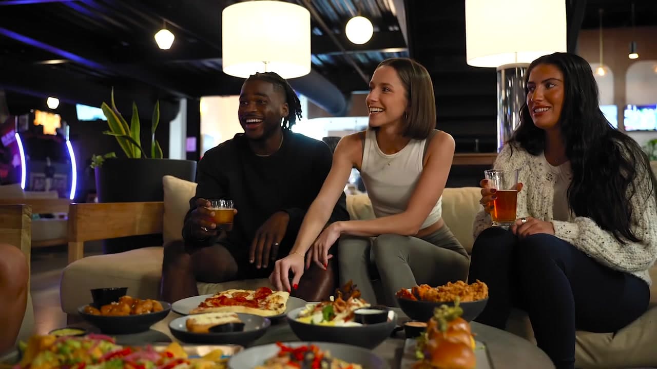 Friends laughing together over food and drinks in the Crush Yard lounge