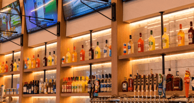 The bar and illuminated bottle shelves at Crush Yard Orlando