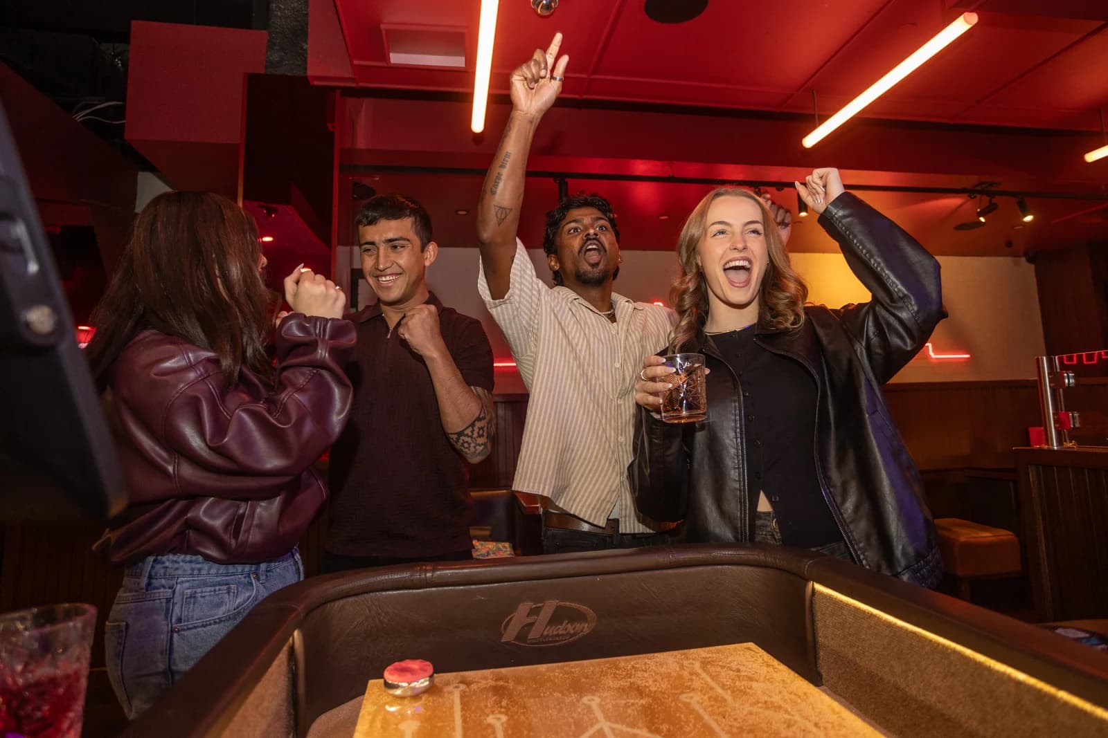 A group celebrating a shot around a Neo Shuffle table