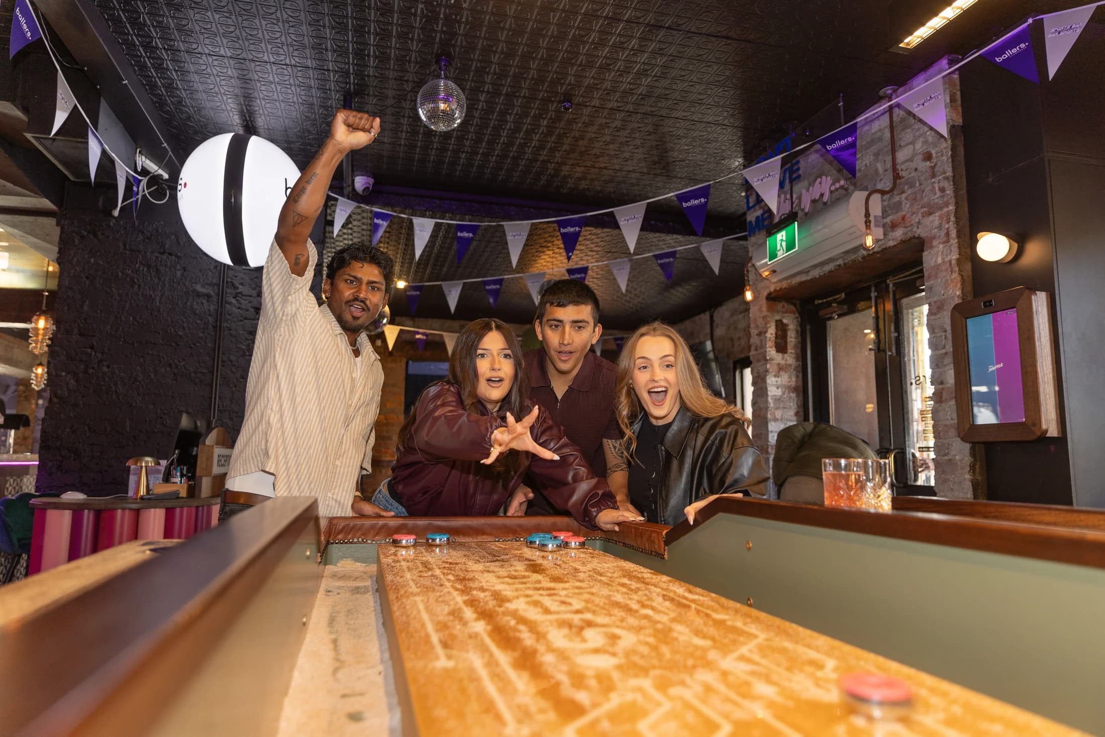 Friends cheering as a puck slides down a Neo Shuffle table